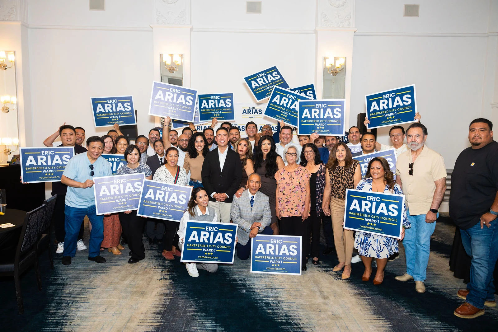Eric Arias surrounded by a large group of campaign supporters holding Arias signs